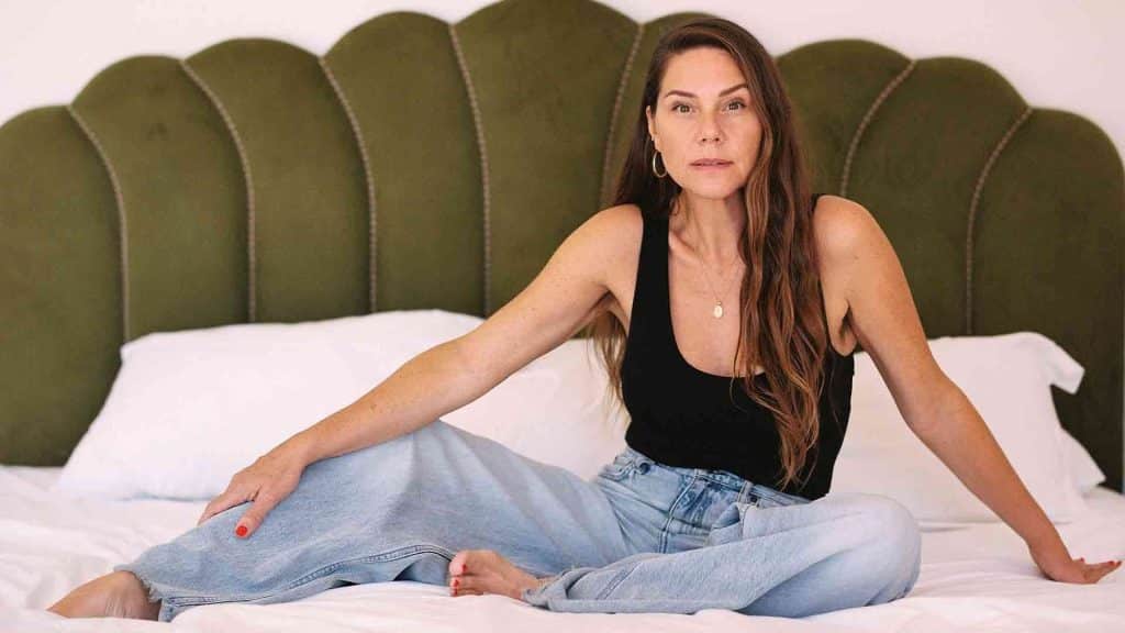 Erika Lust sur un lit, devant une tête de lit en velours vert