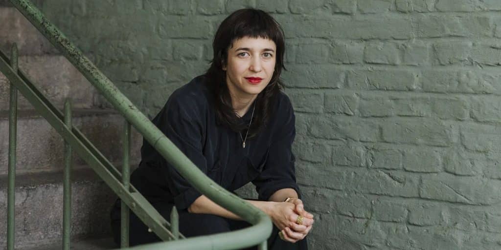 Paulita Pappel assise dans une cage d’escalier aux briques peintes en vert